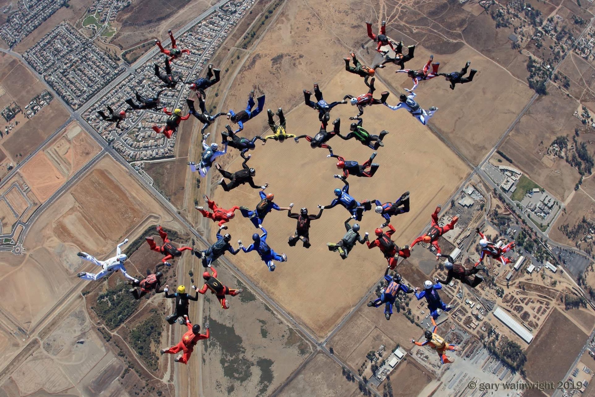 A large skydiving formation seen from above, in concentric rings